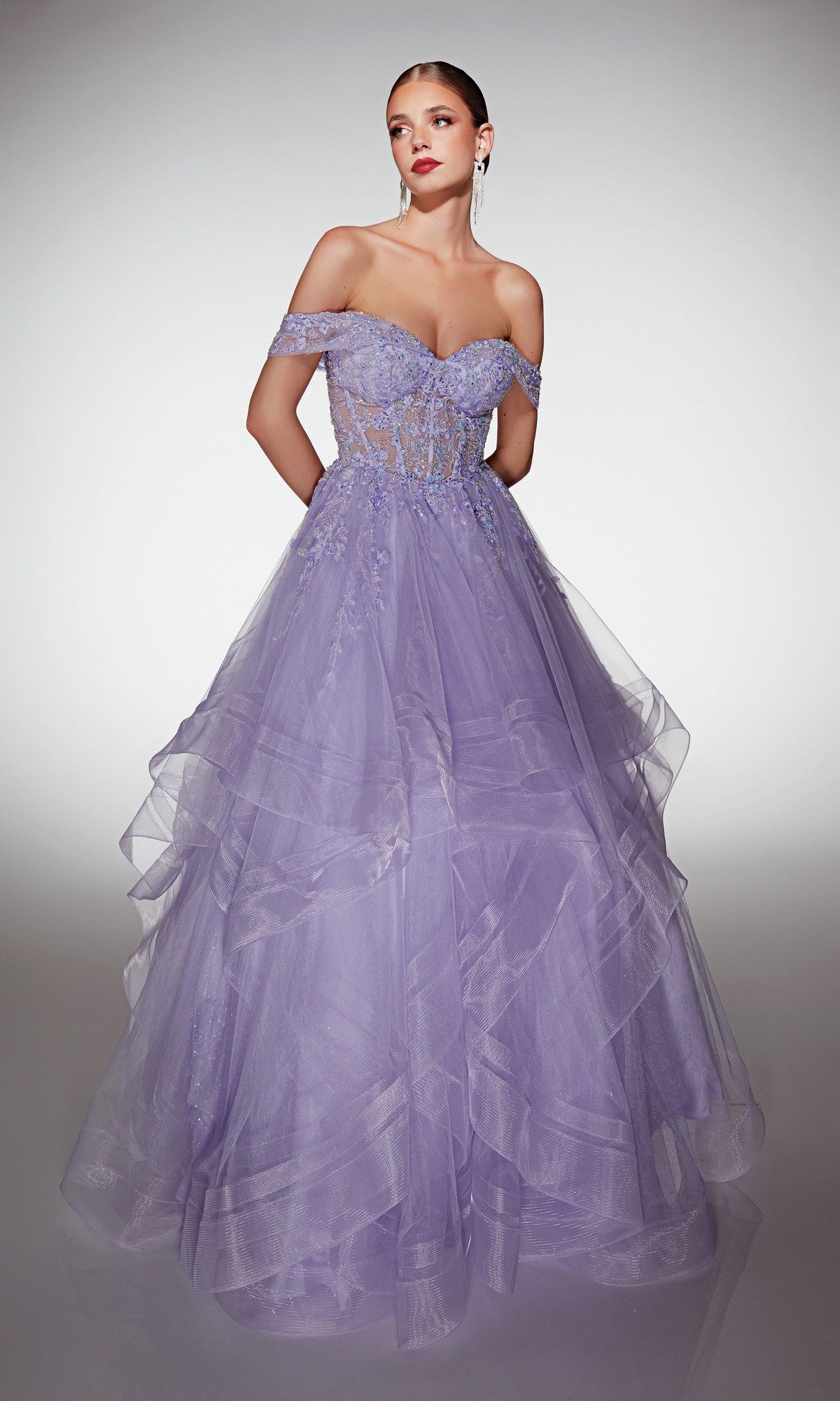 Woman wearing the lilac Alyce 62207 long formal dress, a floor-length, off-the-shoulder tulle ball gown with a sheer bodice, floral lace appliques, and a layered tulle skirt, standing against a plain background.